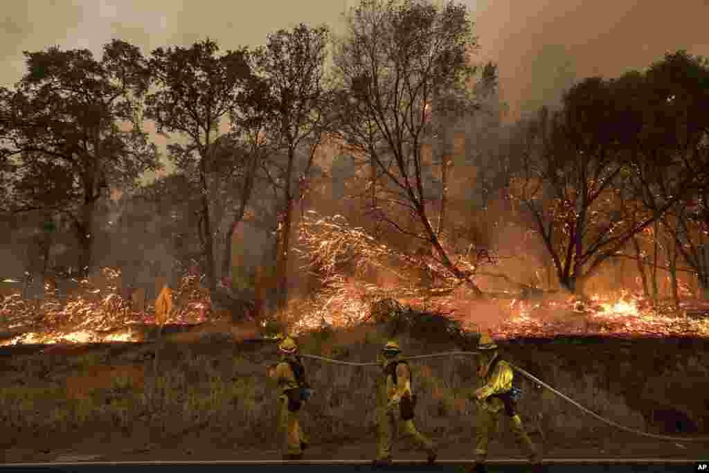 Para pemadam kebakaran berusaha mengatasi kebakaran hutan sebelum melewati jalan raya di Oroville, California.