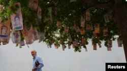 A man sees at Bolivar notes hanging in a tree at a street in Maracaibo, Venezuela, Nov. 11, 2017. 
