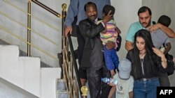 Musa Habib Marika, a Nigerian government representative, (C), carries one of three orphaned siblings linked with the Islamic State, in the Syrian Kurdish-majority city of Qamishli, Sept. 5, 2019. 