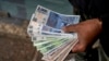 FILE - A vendor holds 'chacho' currency at the Exchange Service Center to convert them to Argentine pesos in La Rioja, Argentina, Sept. 13, 2024. 