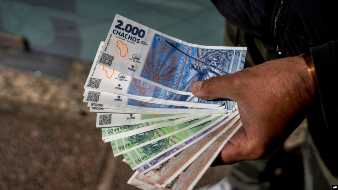 FILE - A vendor holds 'chacho' currency at the Exchange Service Center to convert them to Argentine pesos in La Rioja, Argentina, Sept. 13, 2024. 