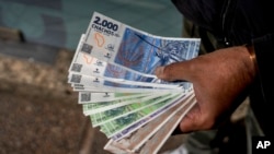 FILE - A vendor holds 'chacho' currency at the Exchange Service Center to convert them to Argentine pesos in La Rioja, Argentina, Sept. 13, 2024. 