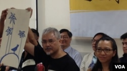 香港政治漫畫家尊子（左）展示一幅為和平佔中運動繪畫的漫畫，寓意香港的民主開花結果