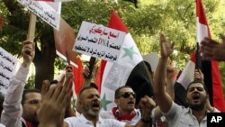 Pro-Syrian regime protesters, shout slogans and hold up an Arabic placard read:"Listen Sarkozy you checked the Syrian people's DNA and you found cells of honor that you don't have," as they protest in front the EU mission office, in Damascus, Sept. 29, 20