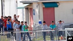 FILE - Children line up to enter a tent at the Homestead Temporary Shelter for Unaccompanied Children in Homestead, Fla., Feb. 19, 2019. The company that runs the center is Comprehensive Health Services, which is part of Virginia-based Caliburn International Corp. 