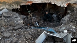 FILE- A Feb. 20, 2015 photo shows eigt-year-old Maxim walking inside the damaged apartment building where his family live, in Debaltseve, Ukraine.