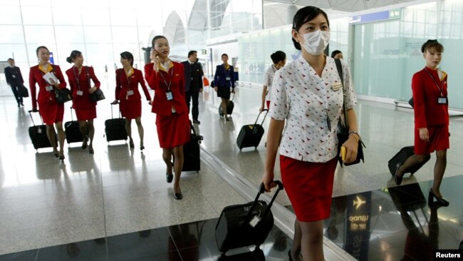 资料照：香港国泰航空公司的空姐在2003年中国非典疫情期间戴口罩上班。（2003年5月15日）