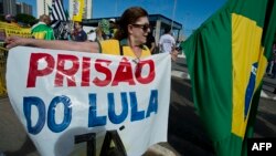 A woman holds a banner reading "Prison for Lula Now" during a demonstration against former President Luiz Inacio Lula da Silva and current President Dilma Rousseff in front of the Criminal Forum in Sao Paulo, Brazil, Feb. 17, 2016. 