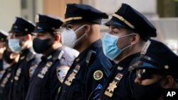 FILE - New York Police Department officers in masks stand during a service at St. Patrick's Cathedral in New York to honor 46 colleagues who have died due to COVID-19 related illness, Oct. 5, 2020. 