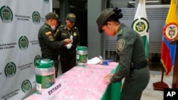 ARCHIVO - Un agente de policía organiza bolsitas llenas de pastillas de MDMA, también conocida como éxtasis, durante una presentación para medios en el Aeropuerto El Dorado de Bogotá, Colombia, el jueves 22 de junio de 2017. 