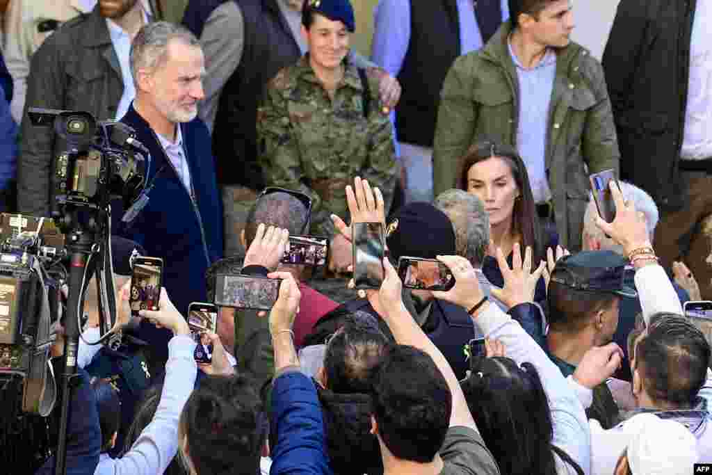 Residents take photos of Spain&#39;s King Felipe VI (L) and Queen Letizia as they visit the flood damaged town of Chiva, in the region of Valencia, eastern Spain, in the aftermath of catastrophic deadly floods.&nbsp;The King and Queen are returning to visit the area after they were heckled by angry residents during their first visit to the Valencia region where catastrophic floods in October left at least 226 people dead, according to officials.&nbsp;(Photo by JOSE JORDAN / AFP)