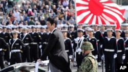 FILE - Japanese Prime Minister Shinzo Abe, center standing, reviews members of Japan Self-Defense Forces (SDF) during the Self-Defense Forces Day at Asaka Base, north of Tokyo, Oct. 23, 2016. Japan is debating whether to develop limited pre-emptive strike capability and buy cruise missiles.