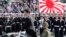 FILE - Japanese Prime Minister Shinzo Abe, center standing, reviews members of Japan Self-Defense Forces (SDF) during the Self-Defense Forces Day at Asaka Base, north of Tokyo, Oct. 23, 2016. Japan is debating whether to develop limited pre-emptive strike capability and buy cruise missiles.