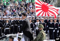 FILE - Japanese Prime Minister Shinzo Abe, center standing, reviews members of Japan Self-Defense Forces (SDF) during the Self-Defense Forces Day at Asaka Base, north of Tokyo, Oct. 23, 2016.