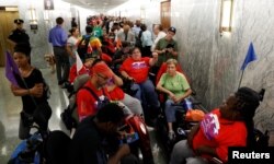 FILE - Protesters, mostly handicapped, line up outside the Senate Finance Committee hearing room hours ahead of a hearing on one of the Republicans' efforts to repeal Obamacare on Capitol Hill in Washington, Sept. 25, 2017.