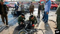 Iraqi security forces inspect a motorcycle at the site of an explosion in Basra, Iraq, Dec. 7, 2021.