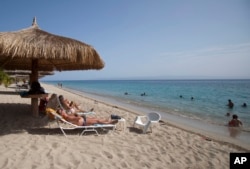 FILE - tourists rest seaside while others wade in the ocean waters at the Club Indigo beach resort in Montrouis, Haiti.