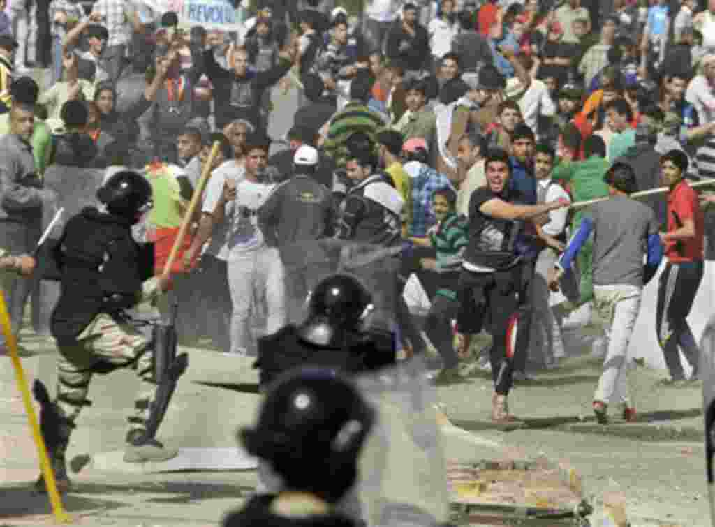 Iraqi anti-government protesters throw stones and trash at riot police during a demonstration in Baghdad, Iraq, Friday, Feb. 25, 2011. Thousands marched on government buildings and clashed with security forces in cities across Iraq on Friday, in the large