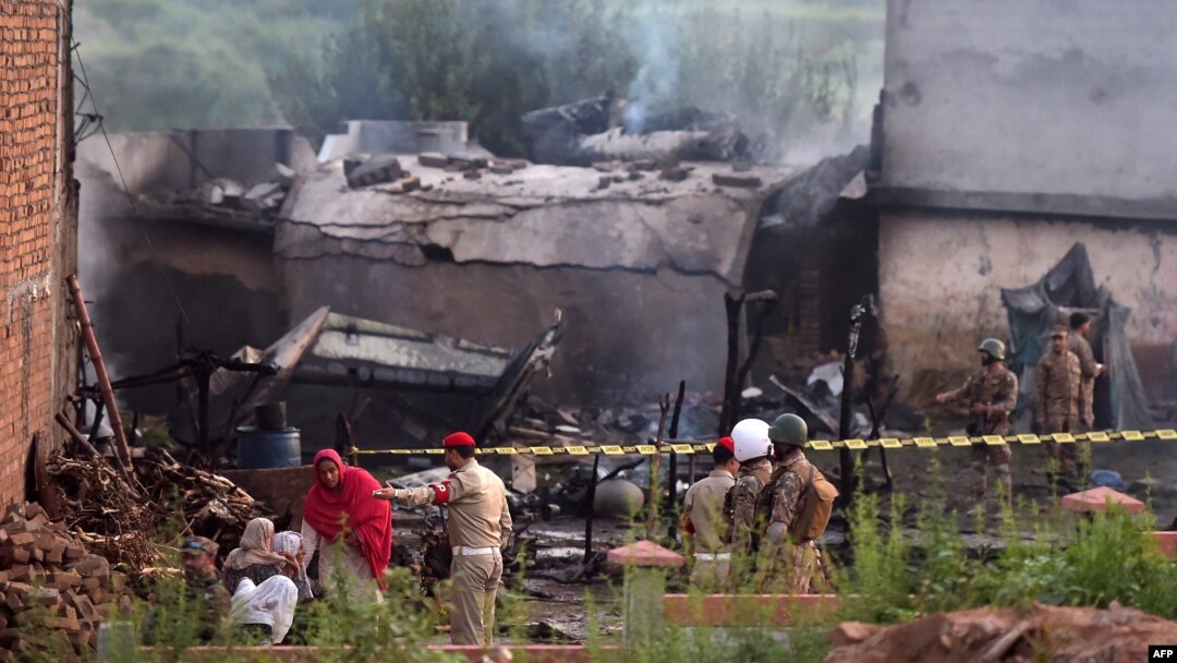 Warga duduk di sekitar puing-puing rumah mereka yang hancur sementar para tentara menutup lokasi tempat pesawat militer Pakistan jatuh di Rawalpindi, 30 Juli 2019. (Foto: AFP)