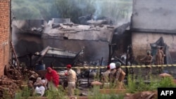 Warga duduk di sekitar puing-puing rumah mereka yang hancur sementar para tentara menutup lokasi tempat pesawat militer Pakistan jatuh di Rawalpindi, 30 Juli 2019. (Foto: AFP)