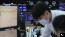 FILE - Currency traders watch monitors at the foreign exchange dealing room of the KEB Hana Bank headquarters in Seoul, South Korea, Nov. 4, 2020. 