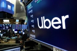 FILE - The logo for Uber appears above a trading post on the floor of the New York Stock Exchange, May 30, 2019.