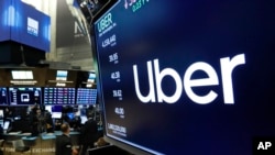 FILE - The logo for Uber appears above a trading post on the floor of the New York Stock Exchange, May 30, 2019.