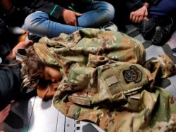 An Afghan child sleeps on the cargo floor of a U.S. Air Force C-17 Globemaster III, kept warm by the uniform of Airman 1st Class Nicolas Baron, during an evacuation flight from Kabul, Afghanistan, Aug 18, 2021. (U.S. Air Force/Handout via Reuters)