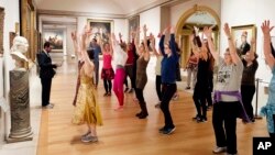 FILE - An exercise group works in front of a bust of Benjamin Franklin at the Metropolitan Museum of Art in New York, Feb. 10, 2017. 