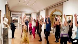 FILE - An exercise group works in front of a bust of Benjamin Franklin at the Metropolitan Museum of Art in New York, Feb. 10, 2017. 