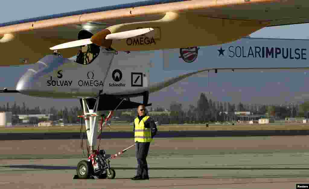 A crew member stands beneath the Solar Impulse to its hangar following a test flight at Moffett Field in Mountain View, California April 19, 2013. The aircraft, made of carbon fiber sheets and powered by solar cells, will attempt to fly once around the wo