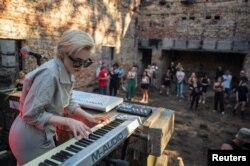 Artist performs while volunteers remove debris from the House of a Culture in the village of Yahidne