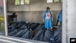 FILE: A Red Cross worker stands next to bodies at a makeshift morgue at a primary school in Bushushu, South Kivu province, Democratic Republic of Congo, on Sat. May 6, 2023.