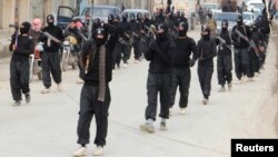 FILE - Fighters of al-Qaida linked Islamic State of Iraq and the Levant carry their weapons during a parade at the Syrian town of Tel Abyad, near the border with Turkey, January 2014.