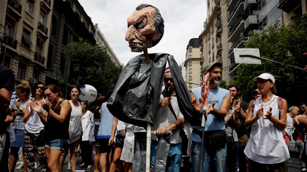 Seorang guru mengacungkan boneka kertas yang mirip Presiden Argentina Mauricio Macri dalam sebuah demonstrasi di Buenos Aires, Argentina, Senin, 5 Maret 2018.