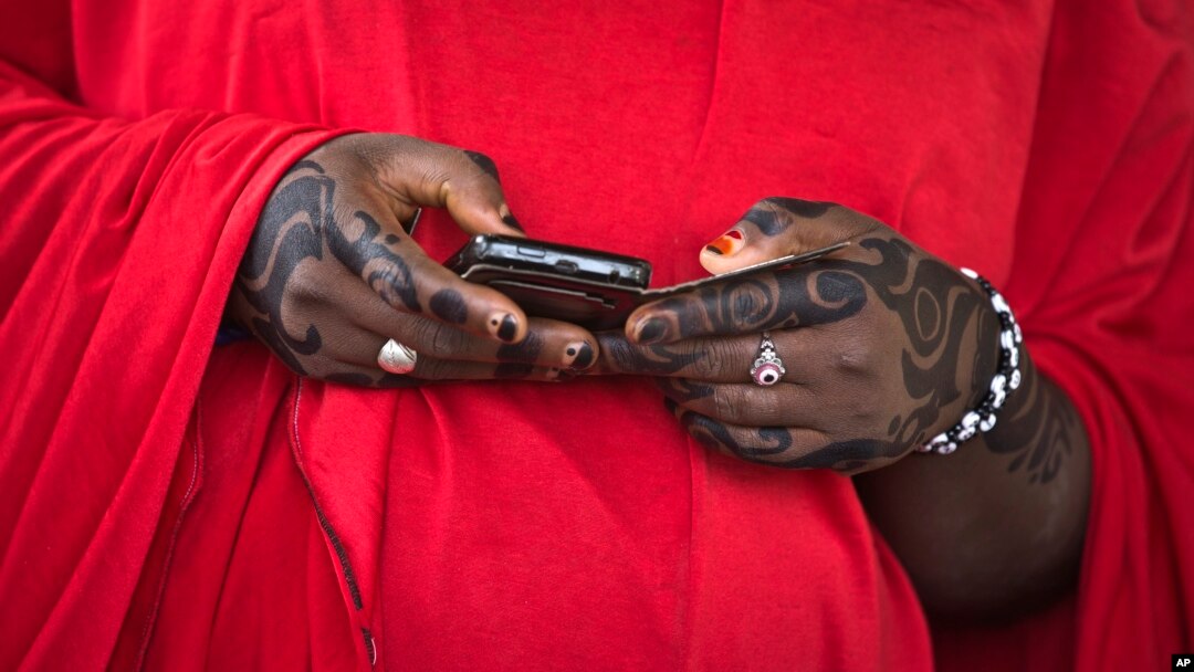 FILE - After voting in at a local Islamic school, a Nigerian women consults her smartphone, March 28, 2015.