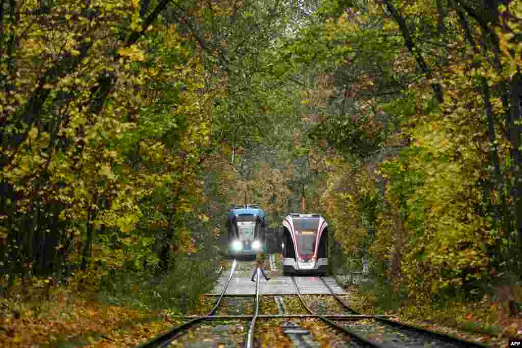 Dua buah trem melewati taman kota pada pagi hari musim gugur yang dingin di Moskow, 20 Oktober 2020.