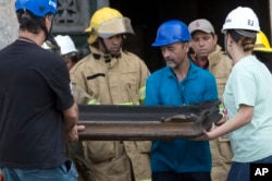 Firefighters and museum personnel carry away a burnt painting from the National Museum after an overnight fire in Rio de Janeiro, Brazil, Sept. 3, 2018.