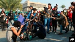 Anti-government protesters use a slingshot to fire a stone at security forces during clashes in Baghdad, Iraq, Jan. 30, 2020.