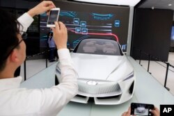 Visitors look at the Infiniti electric concept sedan at a showroom ahead of the Auto China 2018 to be held in Beijing, China, April 19, 2018.