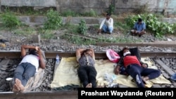 Migrant workers rest on a railway track during a 21-day nationwide lockdown to slow the spreading of coronavirus disease (COVID-19) in in Mumbai, India, April 2, 2020. (REUTERS/Prashant Waydande)