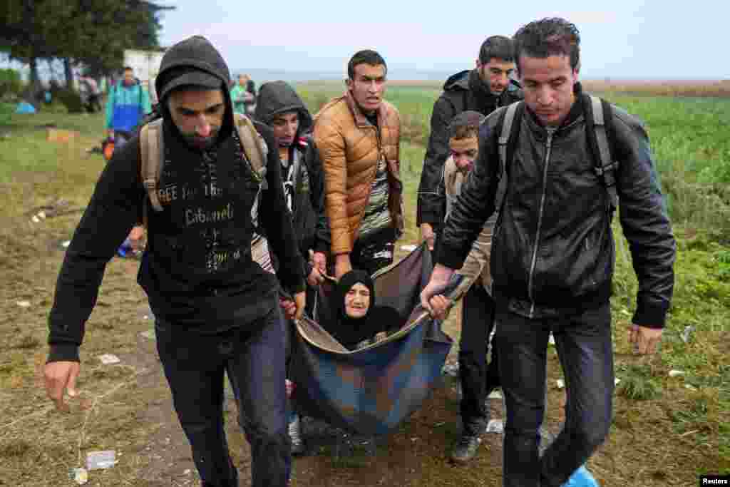 پناهنده گان در حال انتقال یک زن مسن بعد از عبور از مرز صربستان در خاک کرواسی.