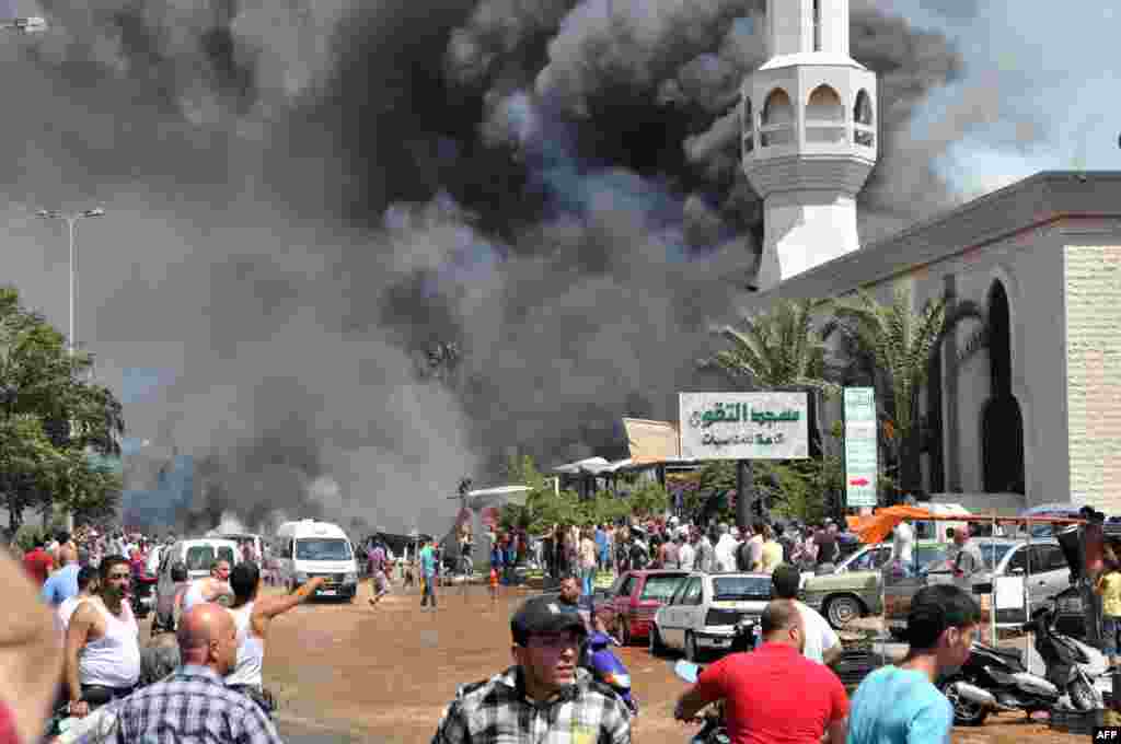 Smoke is seen above people gathering outside a mosque on the site of a powerful explosion in the northern Lebanese city of Tripoli. Two powerful explosions killed several people: one rocked the city center near the home of outgoing&nbsp; Prime Minister Najib Mikati, the second one struck near the port of the restive city with a Sunni Muslim majority.