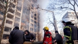 Firefighters and people remove debris after a residential apartment building was hit by shelling as Russia's invasion of Ukraine continues, in Kyiv, Ukraine, March 15, 2022. REUTERS/Thomas Peter