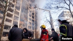 Firefighters and people remove debris after a residential apartment building was hit by shelling as Russia's invasion of Ukraine continues, in Kyiv, Ukraine, March 15, 2022. REUTERS/Thomas Peter