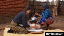 Cameron Beach, left, helps prepare a meal, in Dedza, near Lilongwe, Malawi, Friday, July 23, 2021. (AP Photo/Roy Nkosi)