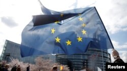 FILE - FILE - A demonstrator holds a European flag during a protest in front of the European Parliament in Strasbourg, France, March 26, 2019. 