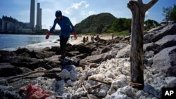 A volunteer collects the congealed palm oil which has been blanketing the shores of Hong Kong's Lamma Island, Aug. 8, 2017.