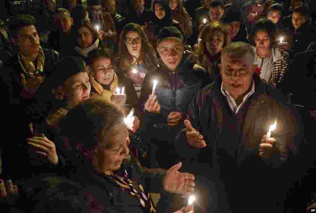 Tunisians holding candles pray at the entrance gate of the National Bardo Museum where scores of people were killed after gunmen staged an attack, Tunis, March 18, 2015.