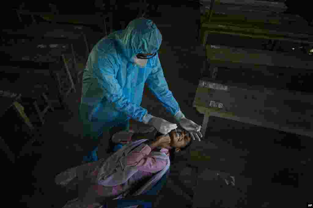 A health worker takes a nasal swab sample of a student to test for coronavirus after classes started at a college in Jhargaon village, outskirts of Gauhati, India.